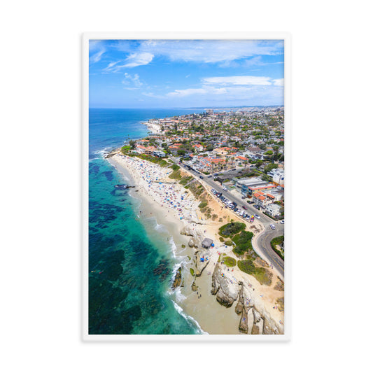An aerial view follows Windansea's turquoise shallows, sandy beach, and oceanfront neighborhood in La Jolla; white frame, 24 × 36 inches.