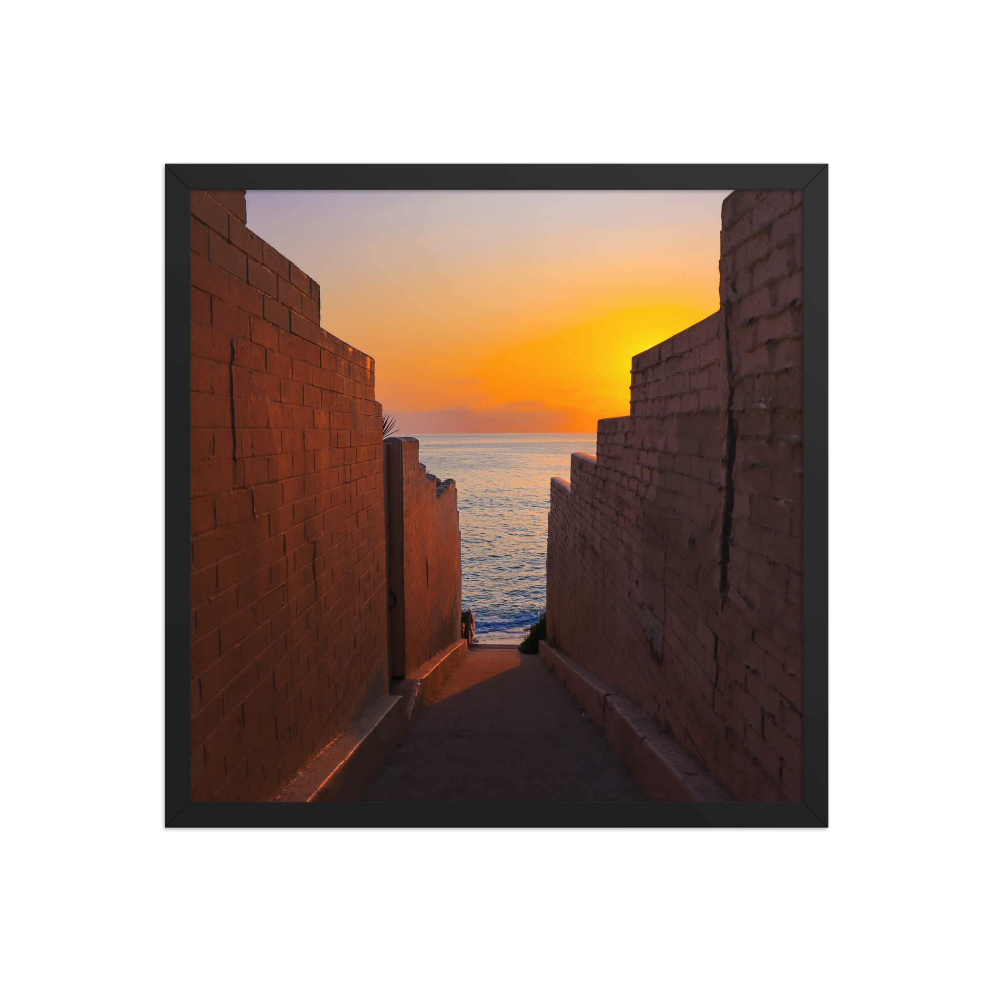 Pink coastal walls frame a narrow ocean view and a glowing sunset at the end of the passage in La Jolla; black frame, 18 × 18 inches.