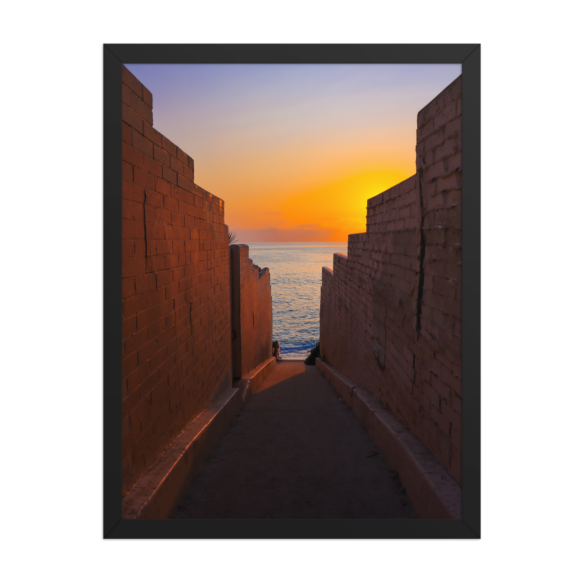 Pink coastal walls frame a narrow ocean view and a glowing sunset at the end of the passage in La Jolla; black frame, 18 × 24 inches.