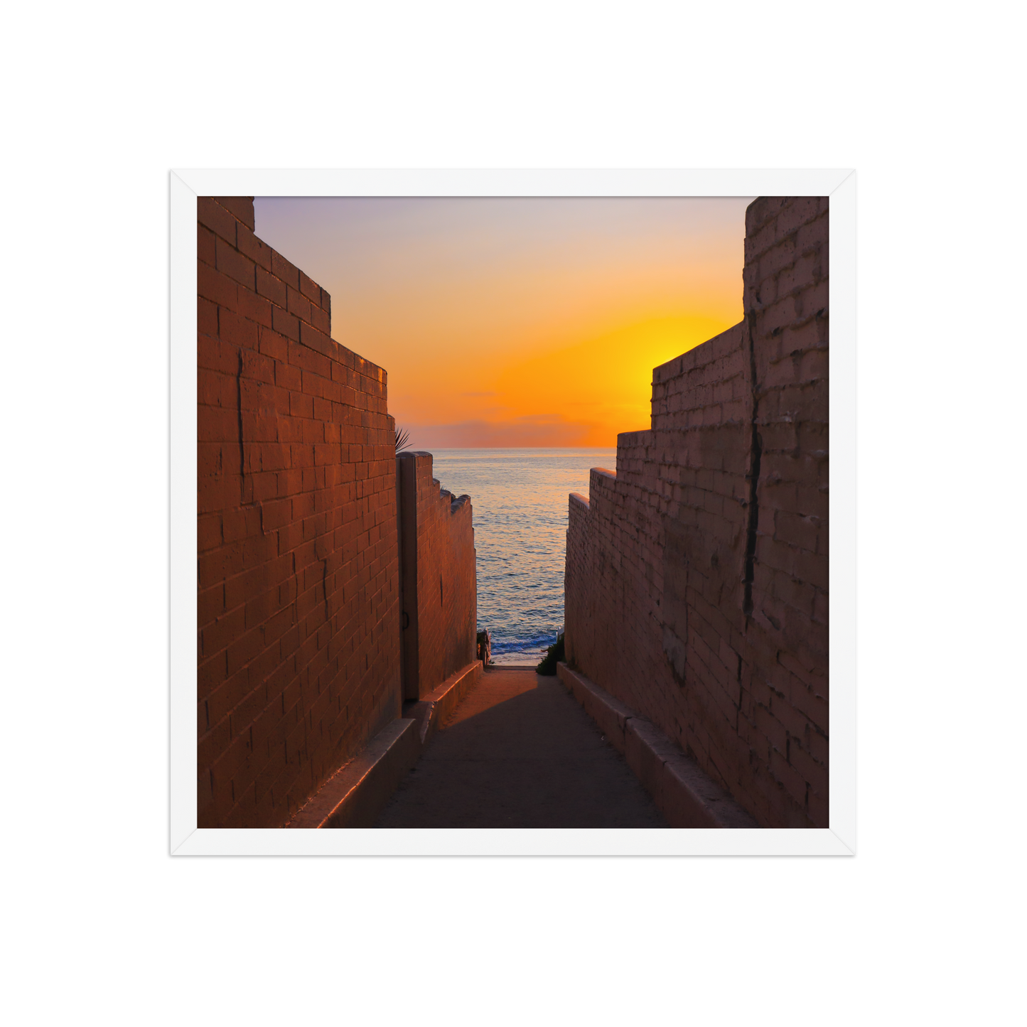 Pink coastal walls frame a narrow ocean view and a glowing sunset at the end of the passage in La Jolla; white frame, 18 × 18 inches.