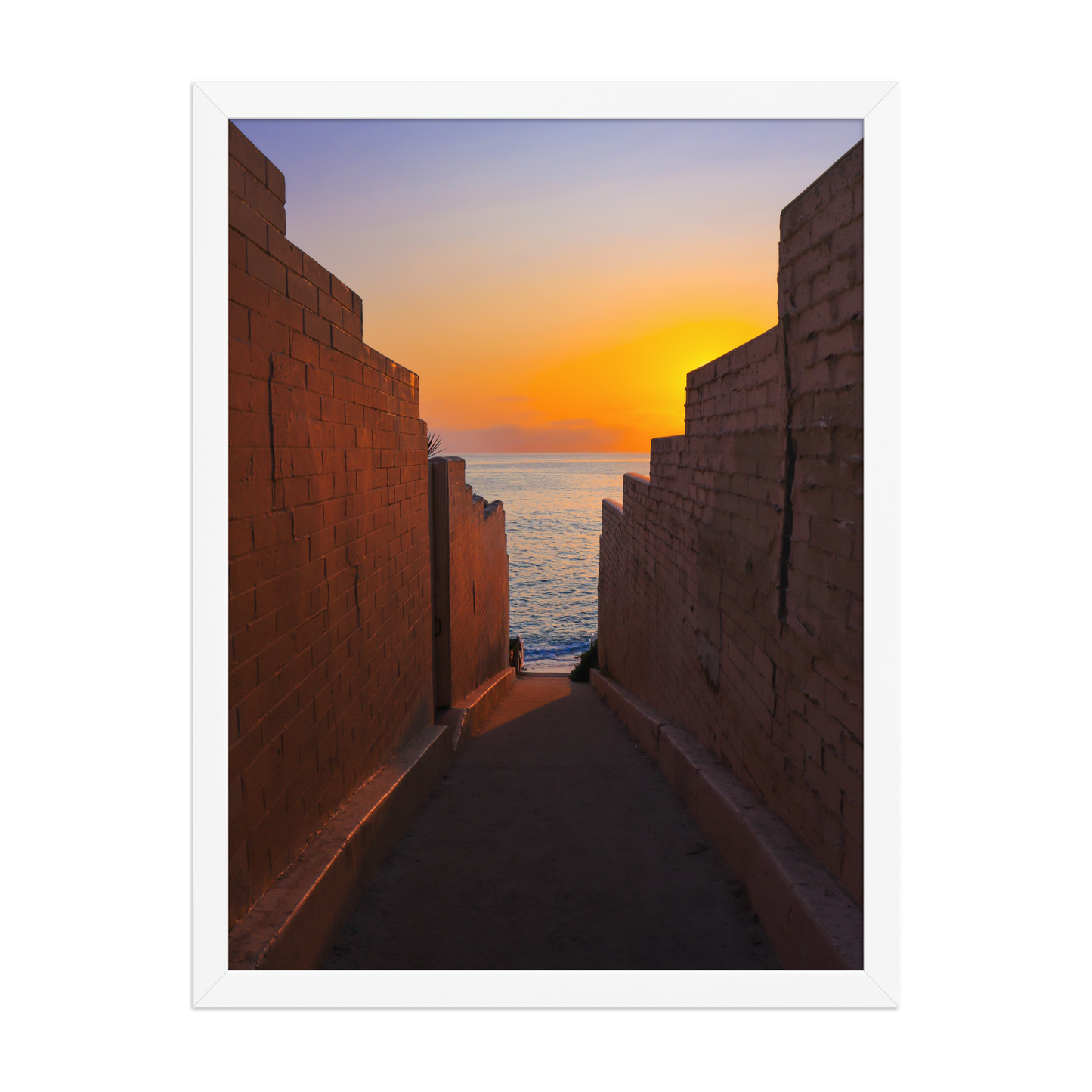 Pink coastal walls frame a narrow ocean view and a glowing sunset at the end of the passage in La Jolla; white frame, 18 × 24 inches.