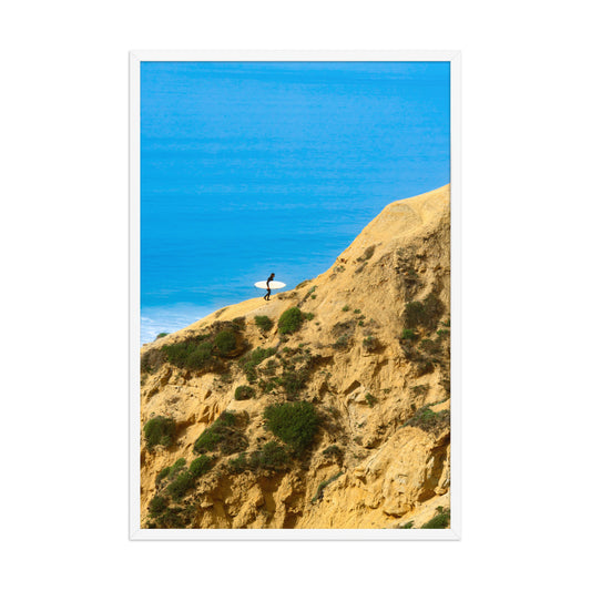 A narrow path winds along a sunlit coastal bluff above deep blue ocean water; white frame, 24 × 36 inches.